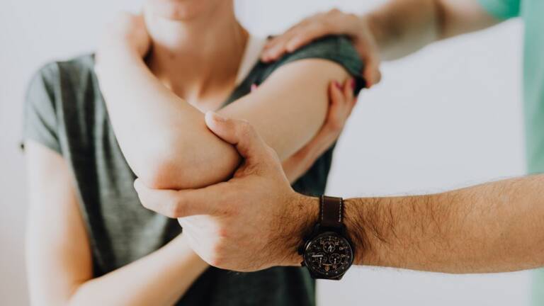 A clinician examining a patient elbow