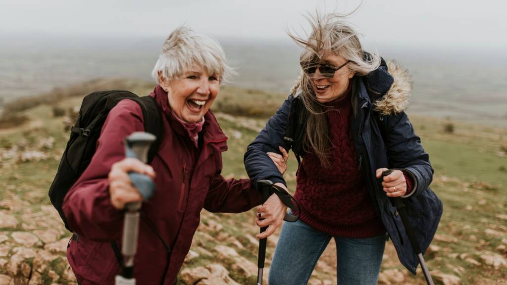 Two women hiking with poles on an open hillside