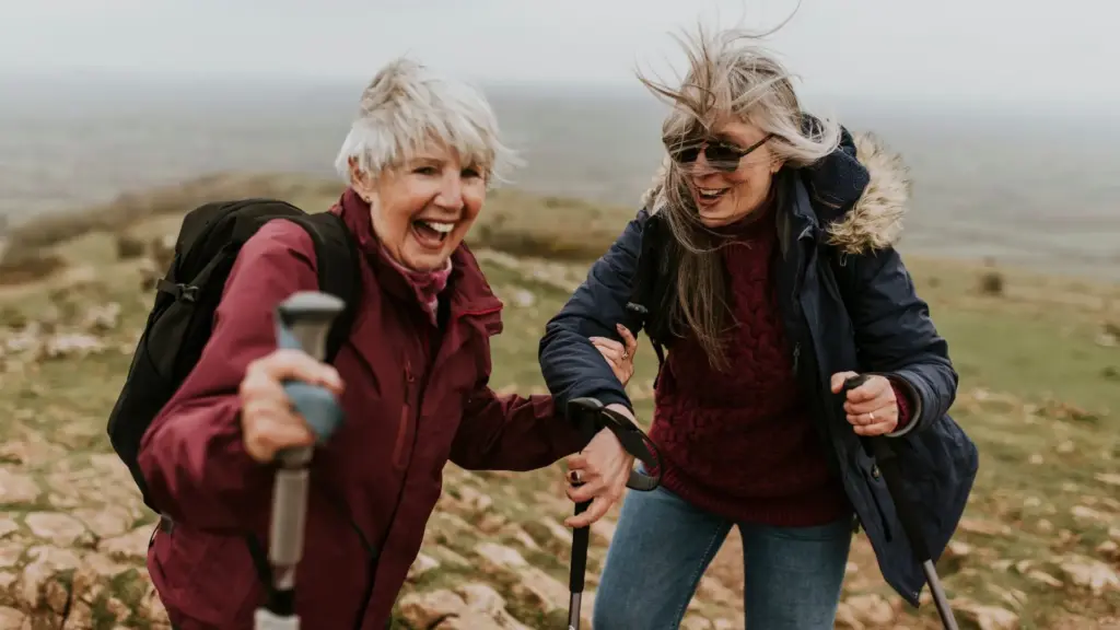 Two women hiking with poles on an open hillside