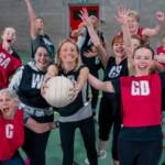 A netball team celebrating together on court