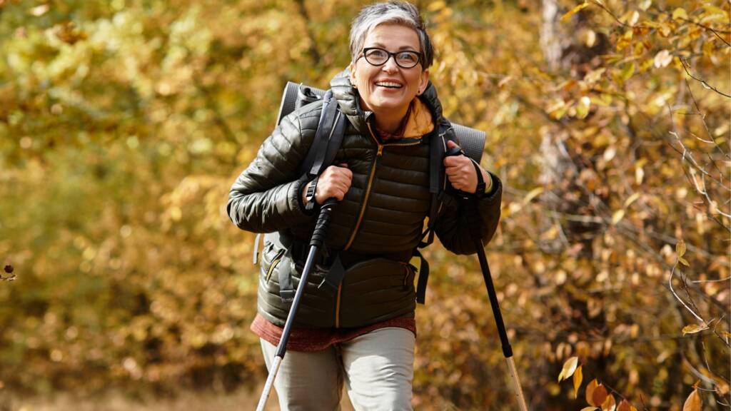 A man walking with trekking poles through autumn woodland