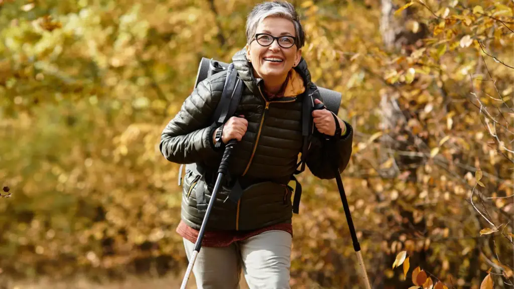A man walking with trekking poles through autumn woodland